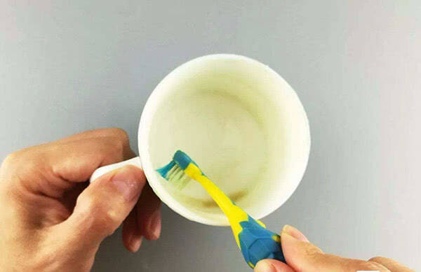 Remove the tea stain inside the teacup with a toothbrush