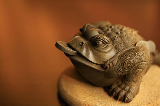 Three-legs golden toad with a coin in the mouth