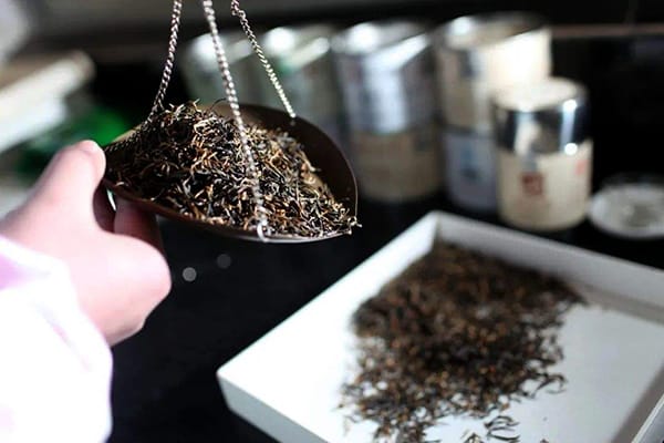 A professional tea master is blending tea leaves